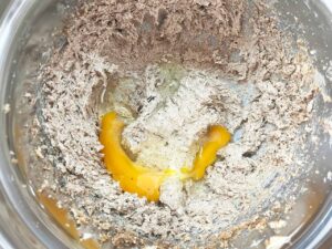 Egg added to a butter and sugar mix in a mixing bowl.