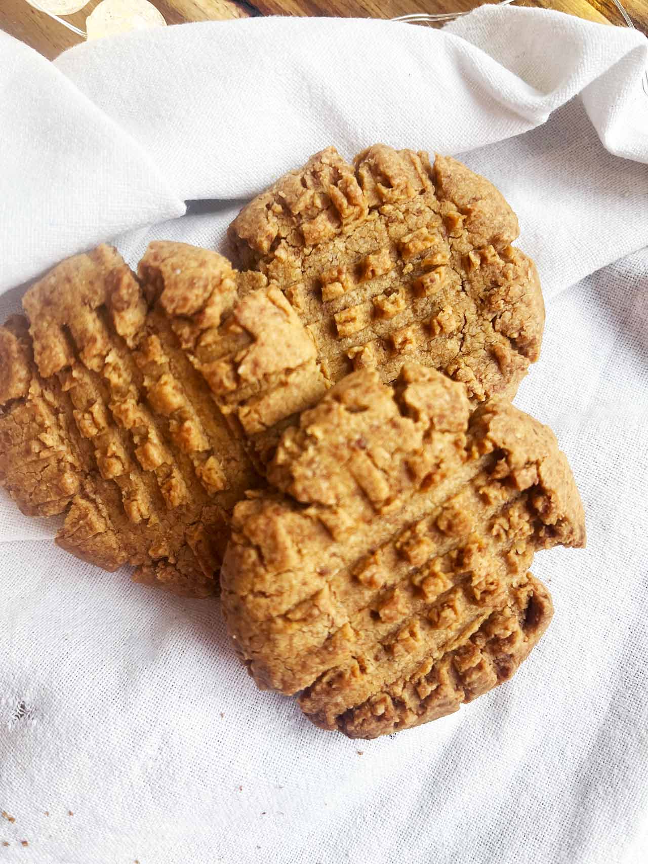 Front view of three Oat Flour Peanut Butter Cookies on a white towel.