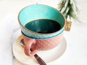 Two stacked mugs sitting on a stack of saucers. Spiced coffee is in the top mug.