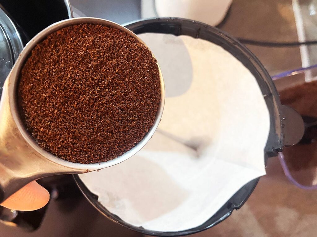 Adding coffee grounds to a paper filter.