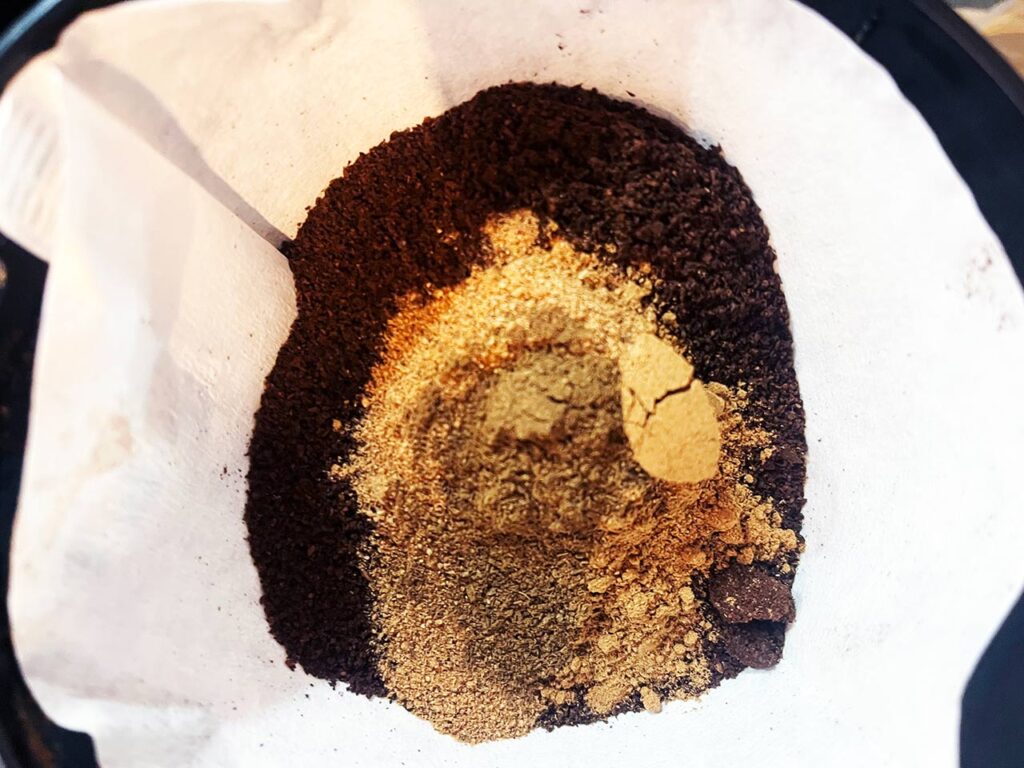 Spices added to coffee grounds in a paper filter.