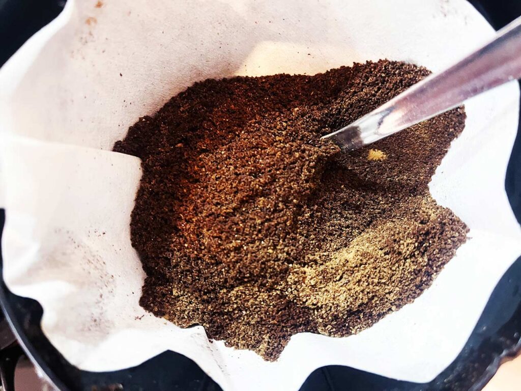 Spices mixed into coffee grounds in a paper filter.