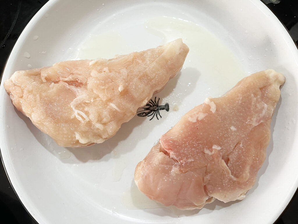 Two chicken breasts on a white plate.