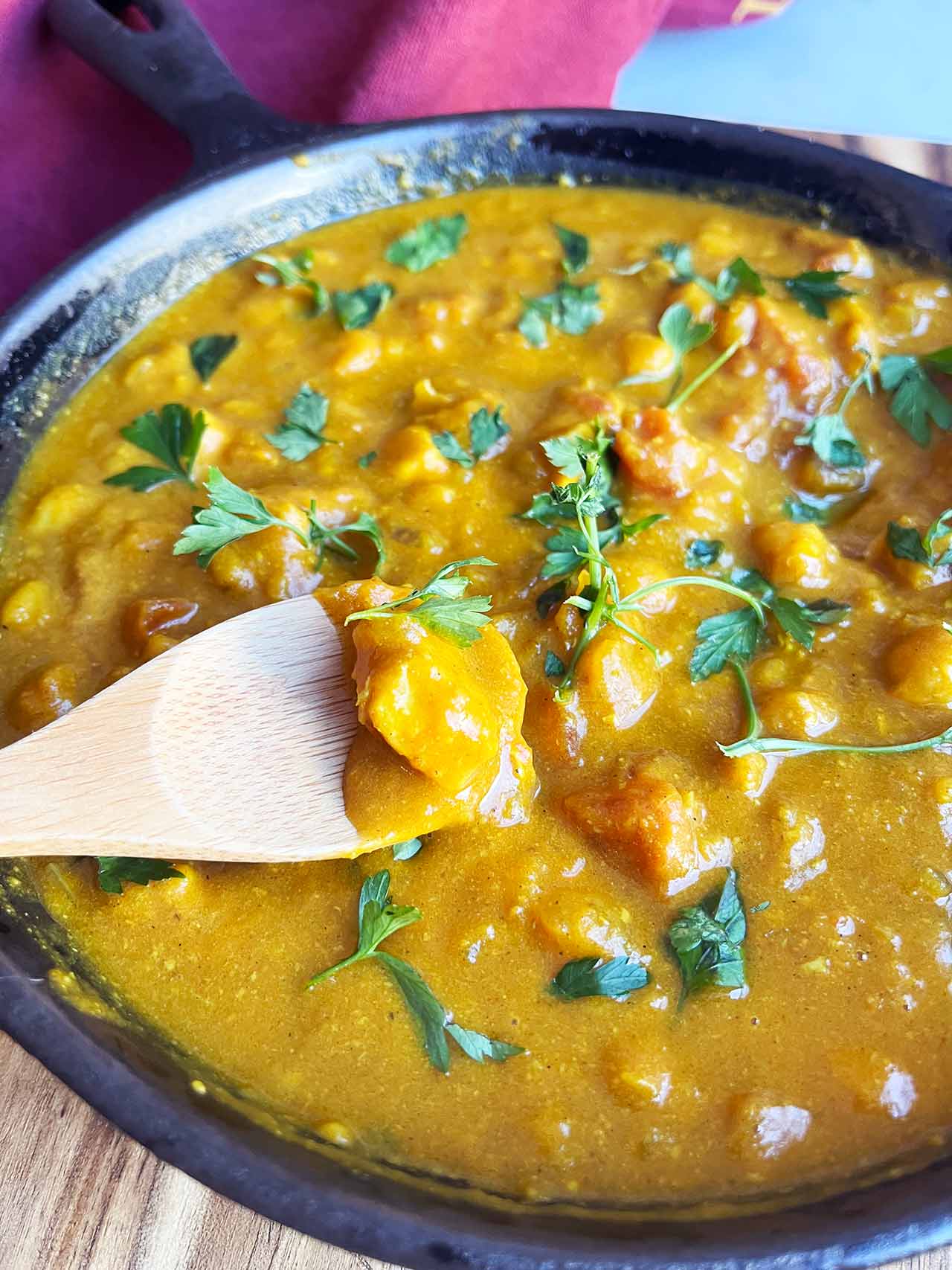A spoon lifts a bit of Pumpkin Curry out of a skillet.