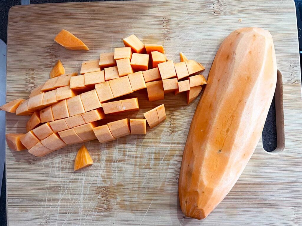 Chopping a sweet potato on a wood cutting board.