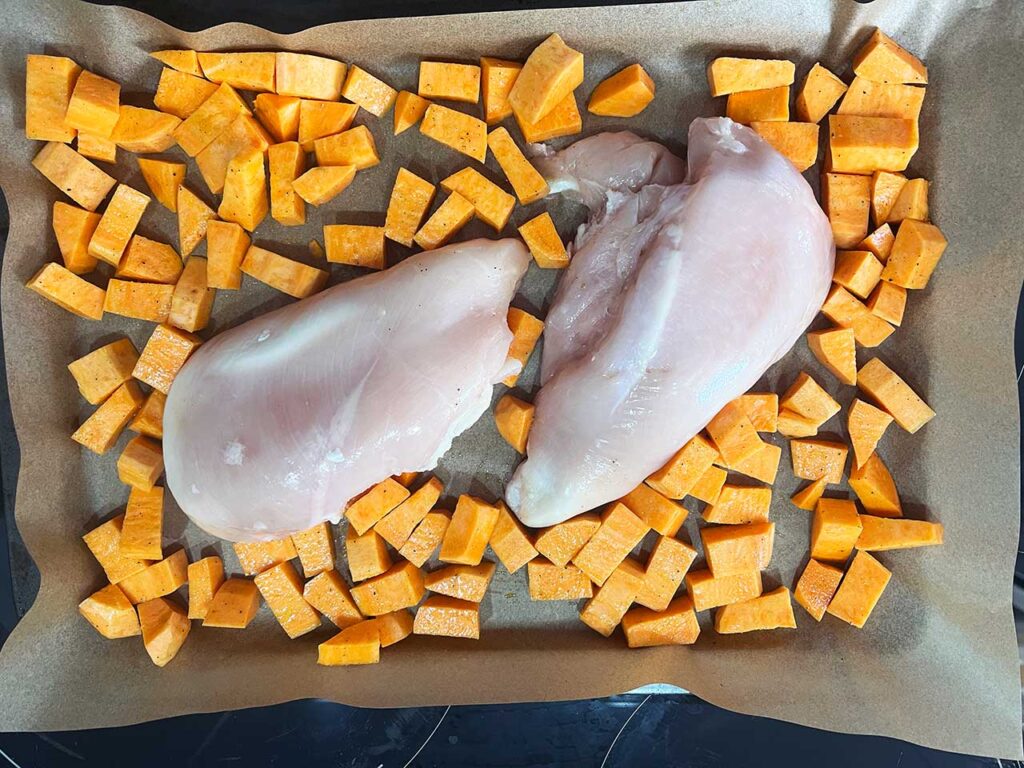 Sweet potatoes added to the sheet pan around the chicken breasts.