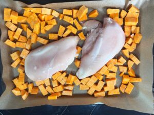 Sweet potatoes added to the sheet pan around the chicken breasts.
