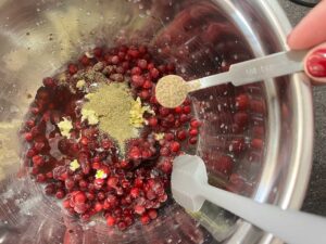 Adding ground black pepper to cranberries in a mixing bowl.