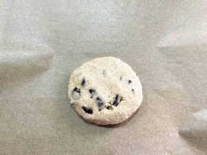 An unbaked chocolate chip cookie on a parchment-lined cookie sheet.
