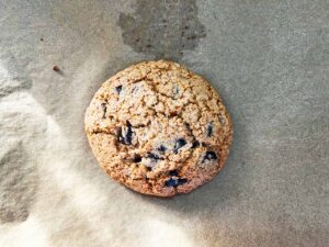 A baked chocolate chip cookie cooling on the pan.