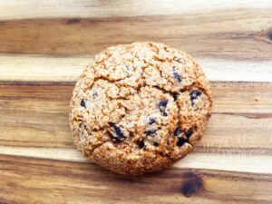 The finished chocolate chip cookie on a wood surface.