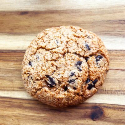 The finished chocolate chip cookie on a wood surface.