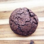 A finished, single chocolate cookie on a wood surface.