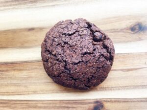 A finished, single chocolate cookie on a wood surface.