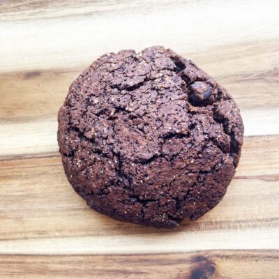 A finished, single chocolate cookie on a wood surface.