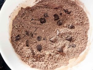 Chocolate chips added to dry ingredients in a mixing bowl.