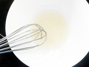 Milk and oil whisked together in a white bowl.