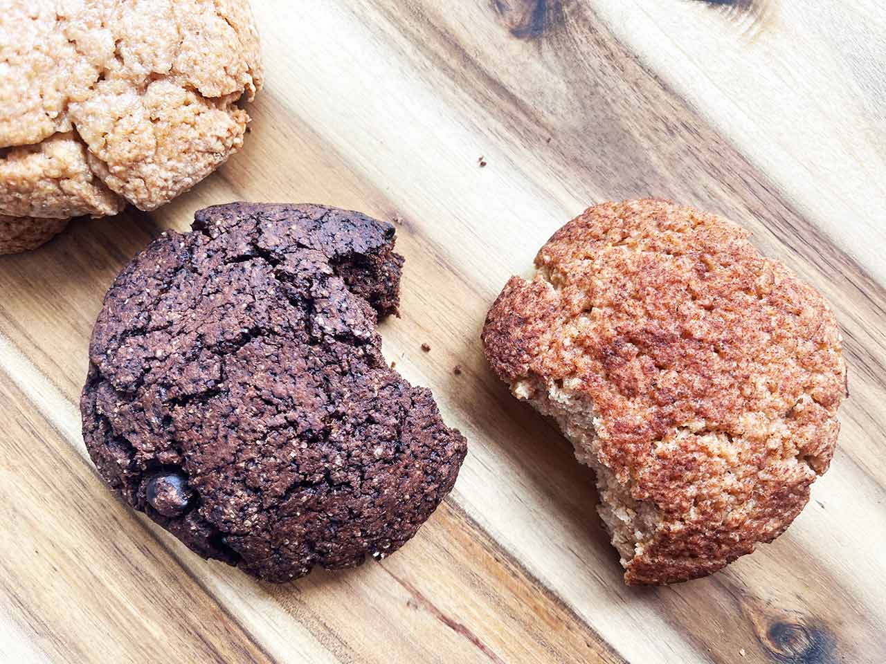 Overhead focus. Three cookies on a wood surface. One sugar, one chocolate, and one snickerdoodle.