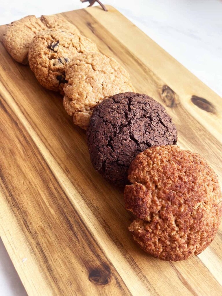 5 cookies lined up on a wood cutting board.