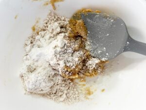 Dry ingredients added to peanut butter mixture in a mixing bowl.
