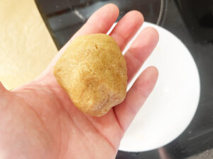 A ball of peanut butter cookie dough held by a hand.