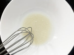 Milk and coconut oil whisked together in a mixing bowl.