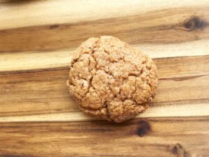 Overhead focus. A single sugar cookie on a wood surface.