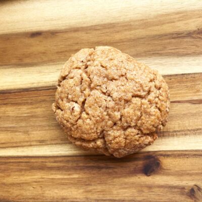 Overhead focus. A single sugar cookie on a wood surface.