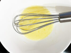 Milk whisked with butter in a mixing bowl.