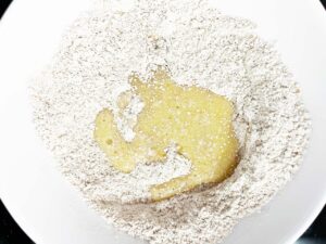 Wet sugar cookie ingredients added to dry ingredients in a mixing bowl.