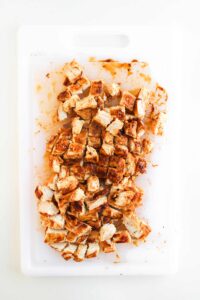 Cook chicken cut into cubes on a white platter.