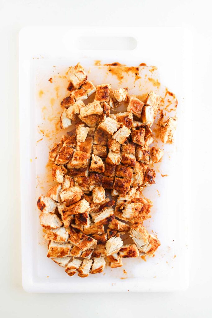 Cook chicken cut into cubes on a white platter.