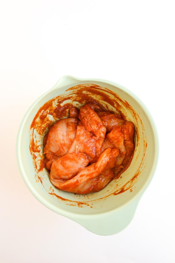 Chicken mixed into red sauce for Street Corn Chicken Tacos .