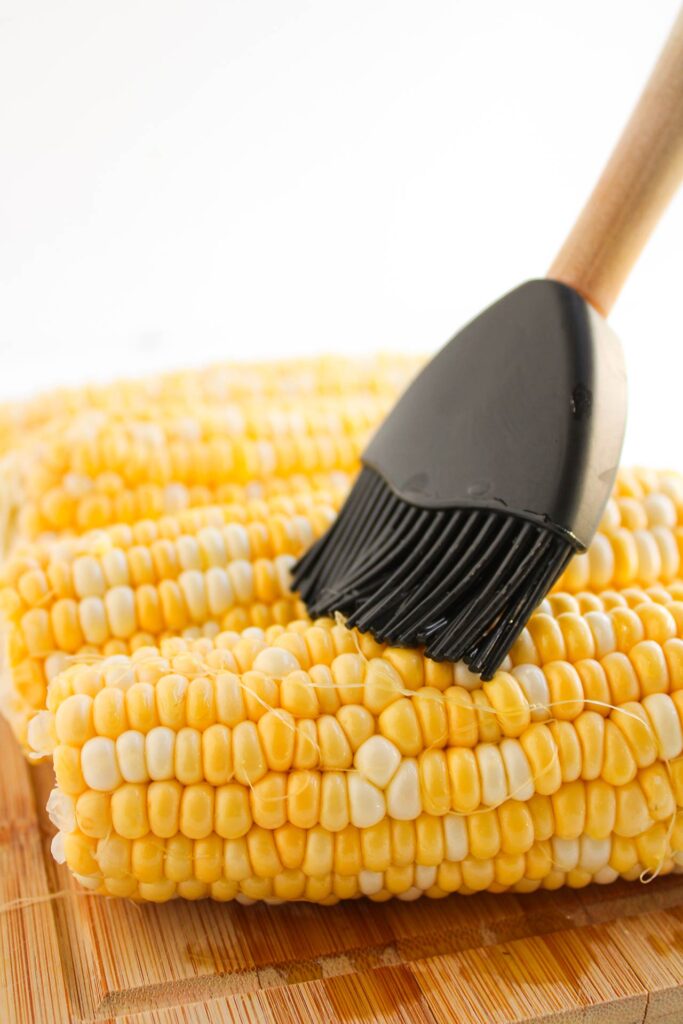 Brushing corn with butter.