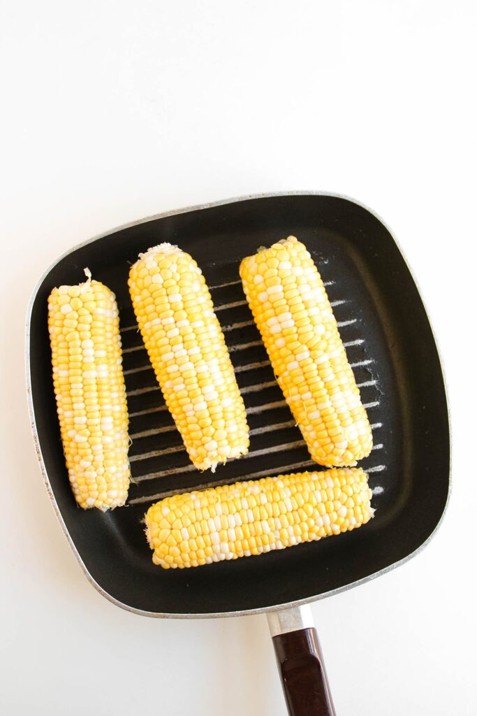 Cooking corn on the cob on a grill skillet.