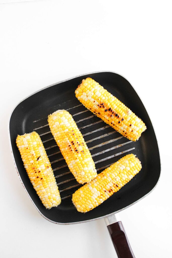 Charred corn on the cob on a grill skillet.