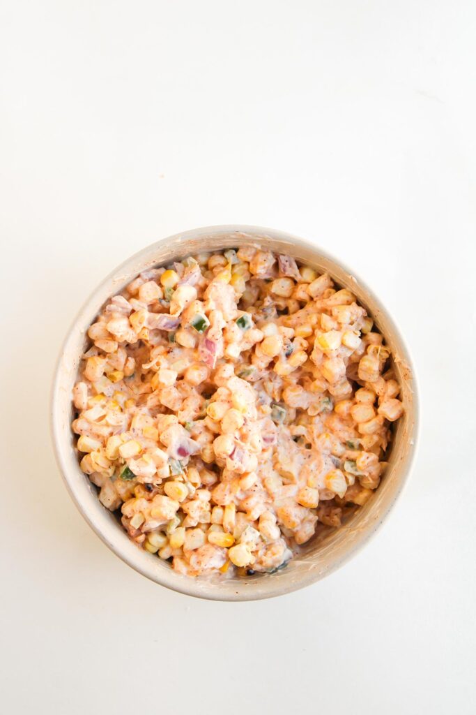 Street corn topping mixed and ready to use in a white bowl on a white surface. Overhead focus.