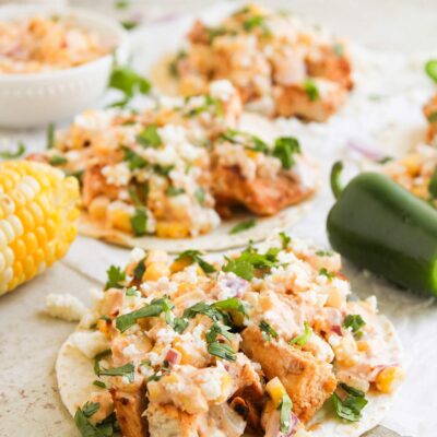 Front focus. Street Corn Chicken Tacos lined up on parchment paper.