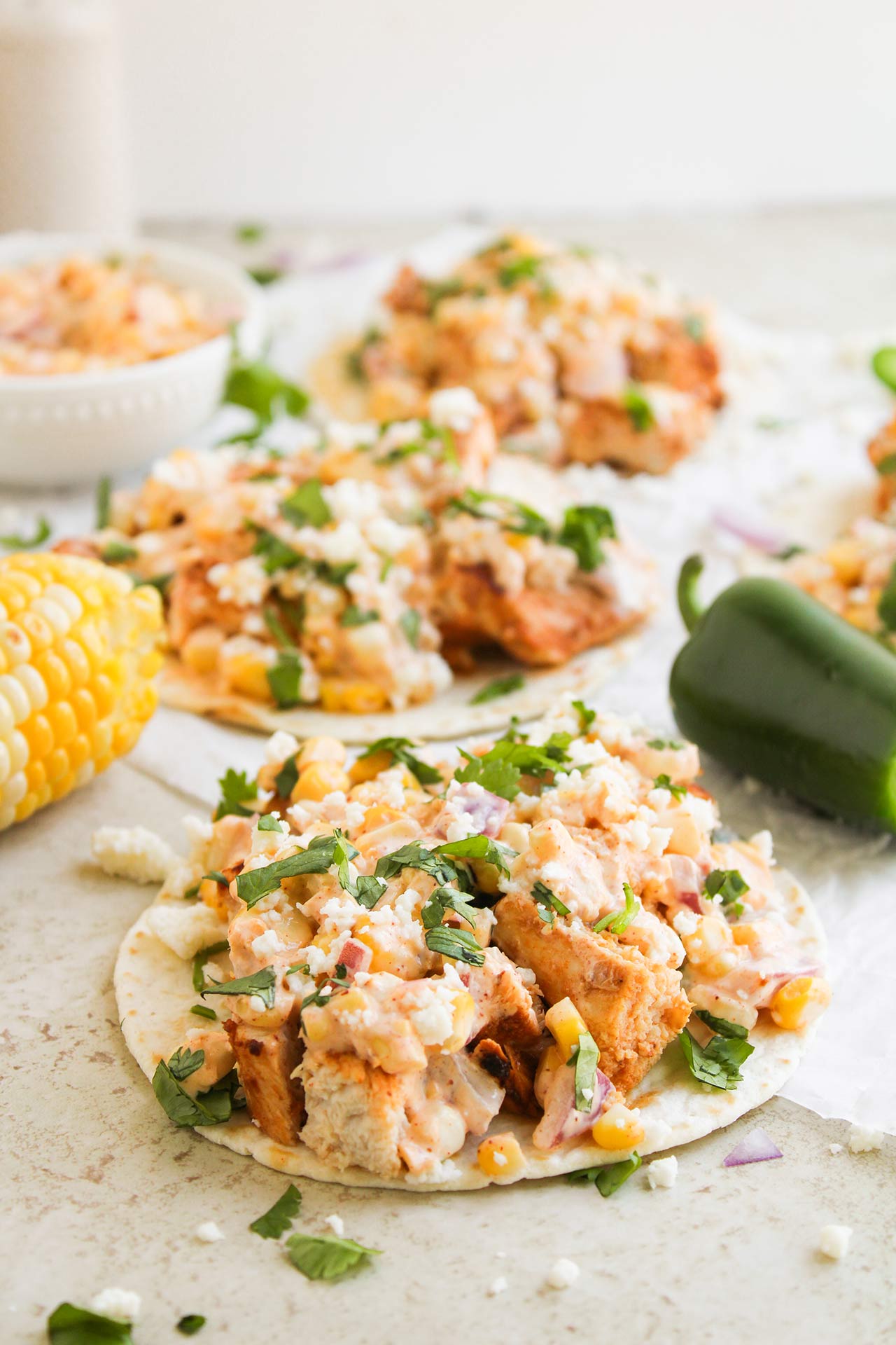 Front focus. Street Corn Chicken Tacos lined up on parchment paper.