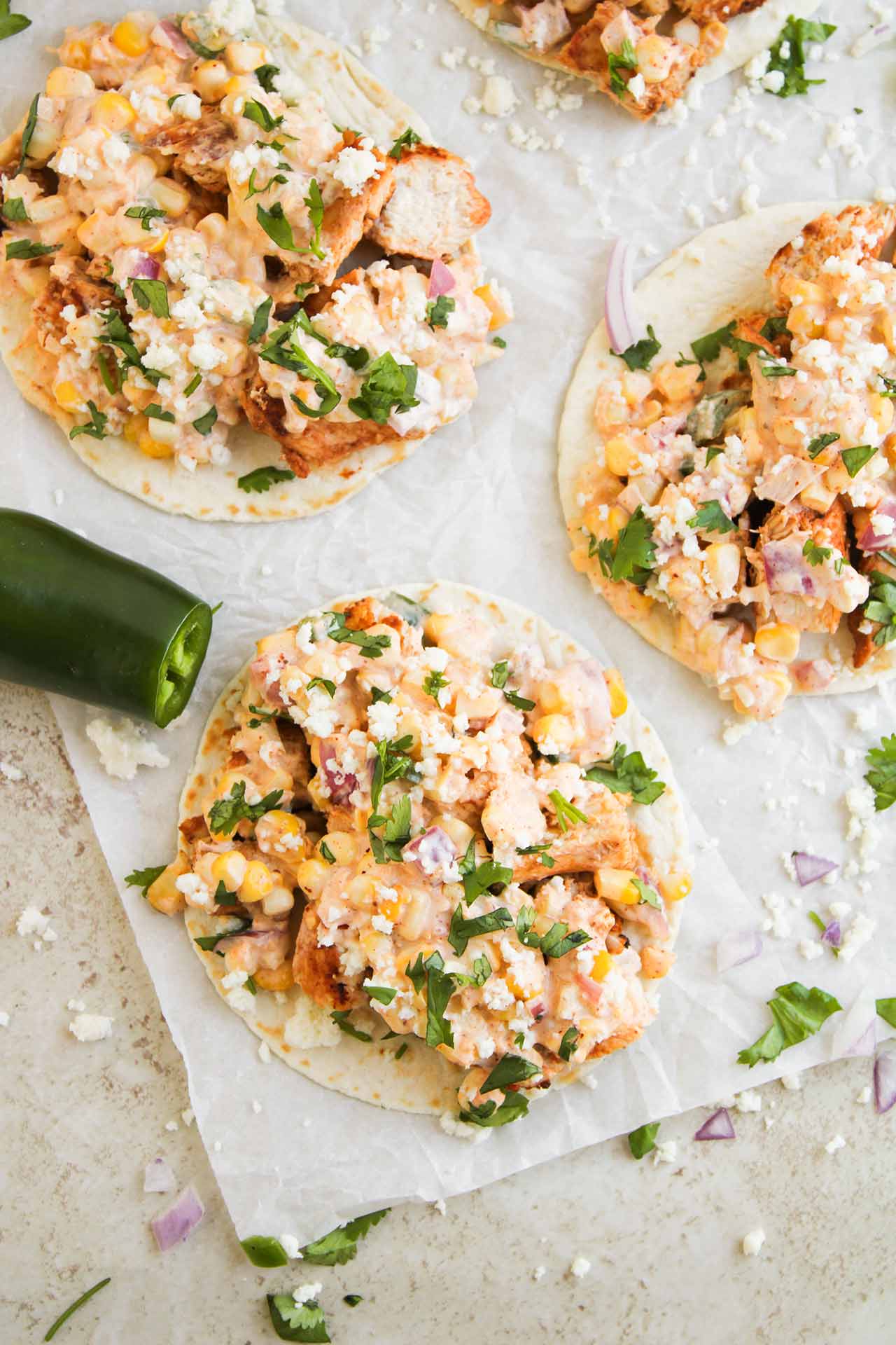 Closeup overhead focus. Four Street Corn Chicken Tacos on parchment.