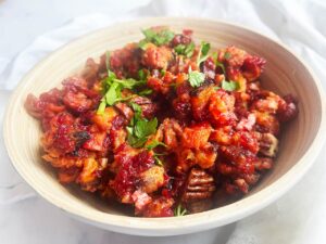 Front view. A wood bowl filled with Sweet Potato Cranberry Salad .