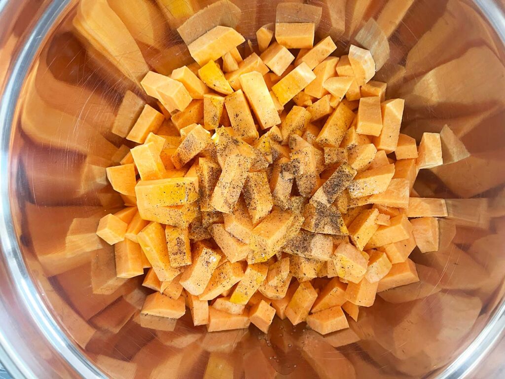 Cut sweet potatoes in a mixing bowl with oil, salt, and pepper added.