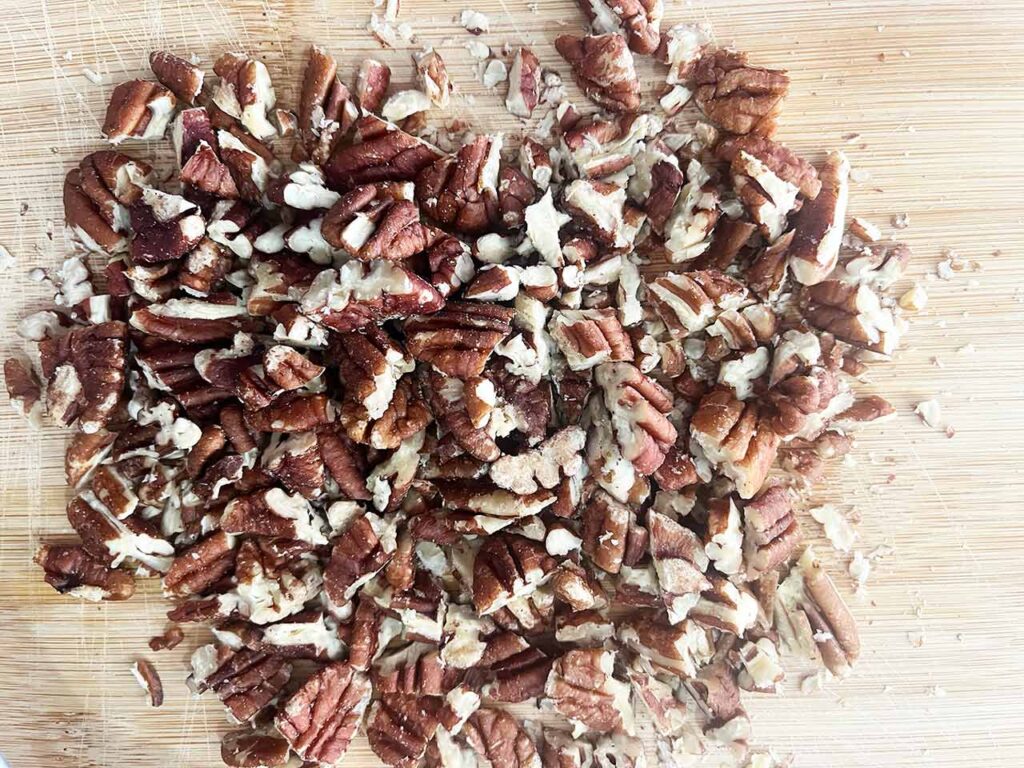 Toasted pecans, chopped and laying on a cutting board.