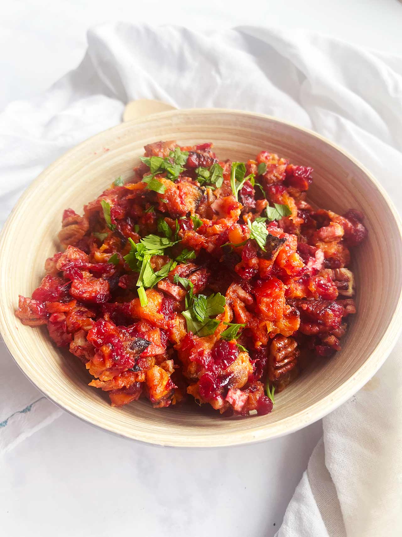 Angled focus. A wood bowl full of Sweet Potato Cranberry Salad .