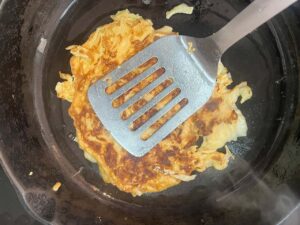 Pressing the pancake to show no raw egg. This is when it's done.