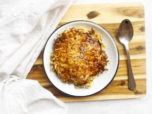 Topping Cabbage Pancakes with sesame oil, coconut aminos, and sesame seeds.