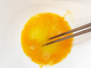 Lightly beaten eggs in a mixing bowl.