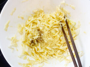 Adding coconut aminos to the cabbage and eggs.