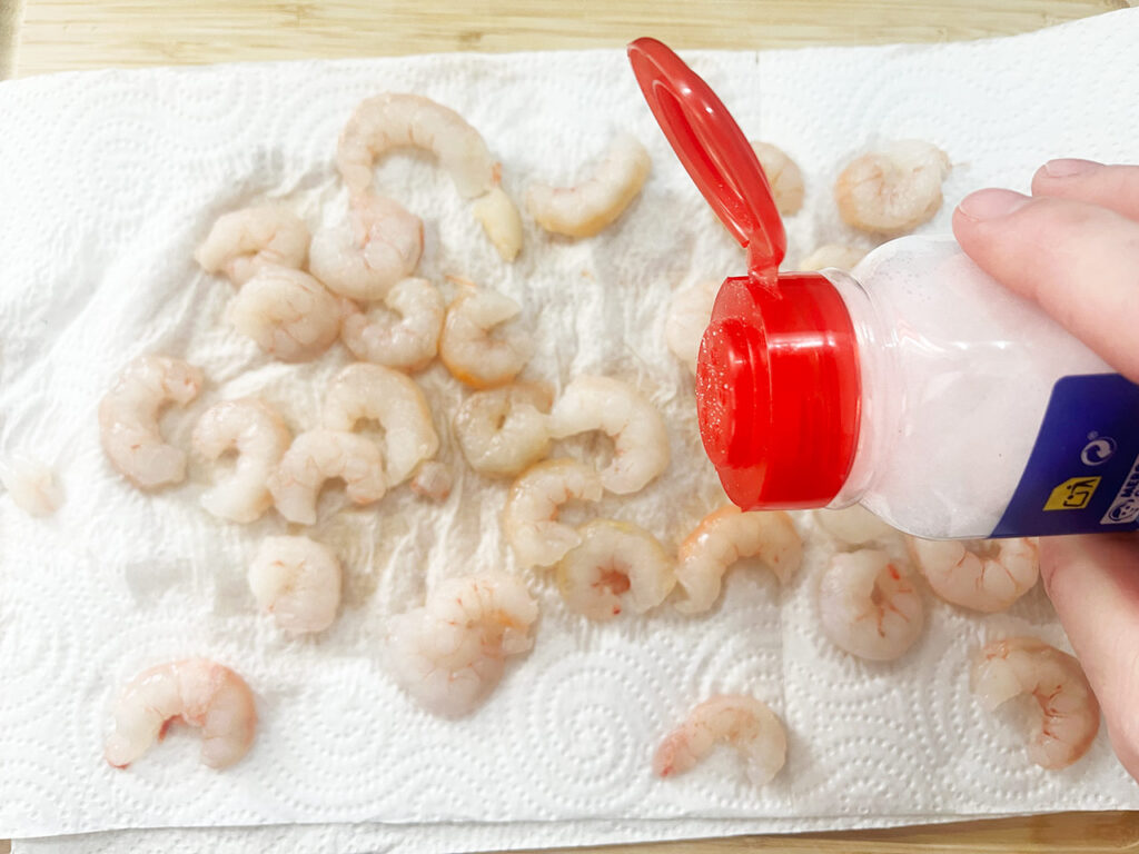 Sprinkling raw shrimp lightly with salt.