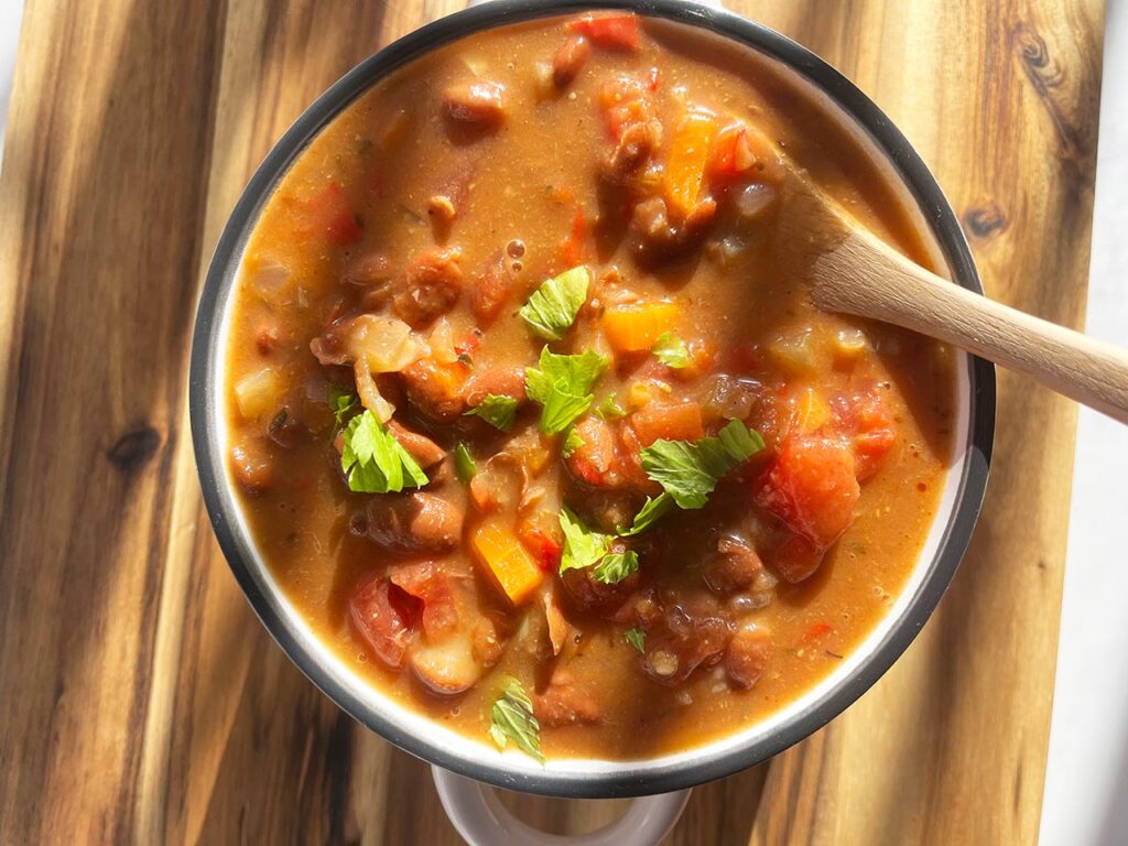 Overhead focus. A full bowl of Mexican Pinto Bean Soup sitting on a wood surface.